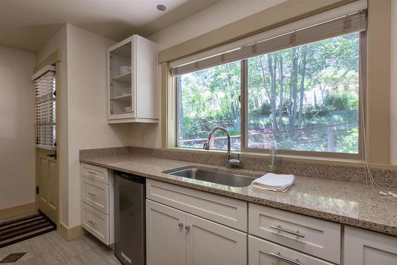 Full kitchen with white cabinets, granite countertops, and forest views at Palisades Tahoe Studio